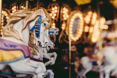 Close-up of carousel horse sculptures at illuminated amusement park