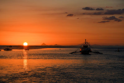 Sailboat sailing in sea against sky during sunset