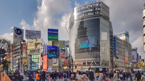 People on street against modern buildings in city