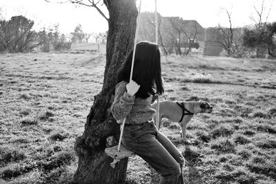 Girl by dog on swing at field