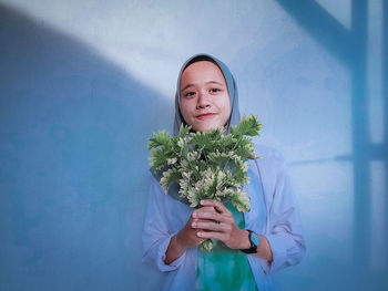 Portrait of young woman standing against wall