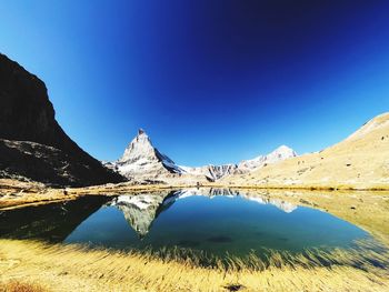 Scenic view of snowcapped mountains against clear blue sky