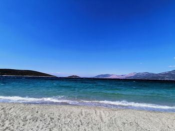 Scenic view of beach against clear blue sky