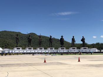 Group of people on road against clear blue sky