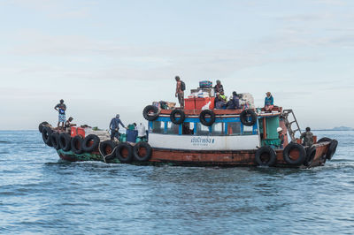 People on boat in sea against sky