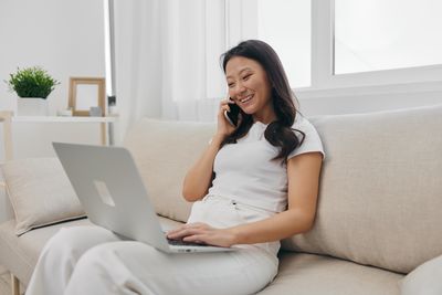 Businesswoman using laptop while sitting on sofa at home