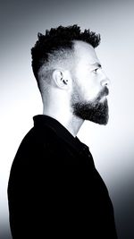 Portrait of young man looking away against gray background