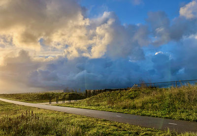 Road amidst field against sky