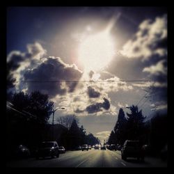 Cars on road against cloudy sky