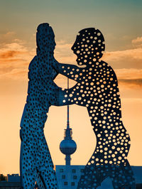 Shadow of man and woman standing against sky during sunset