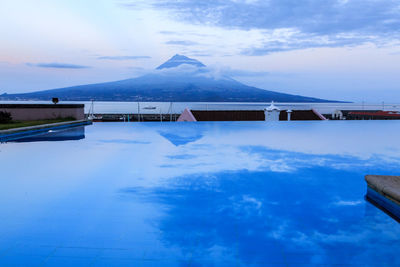  panoramic view of mountains reflected in swimming pool against blue sky