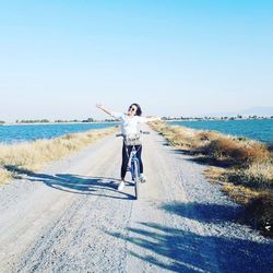 Man riding bicycle on road against clear sky
