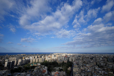 Aerial view of cityscape by sea against sky