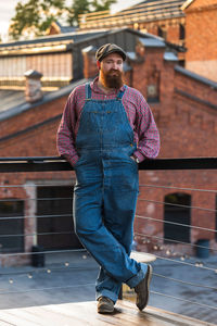 Full length portrait of young man standing against building in city