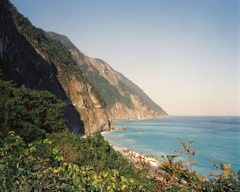 Scenic view of sea against clear sky and rocky cliffs