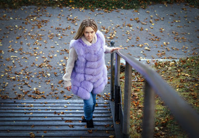 High angle portrait of woman on steps at park during autumn