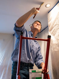 Low angle view of man painting ceiling