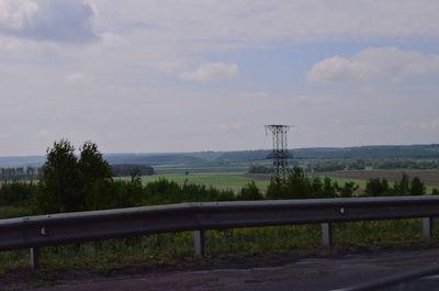 Electricity pylon by road against sky