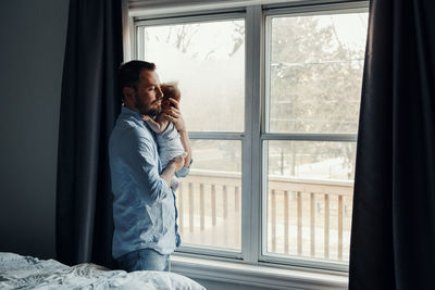 Man looking through window at home