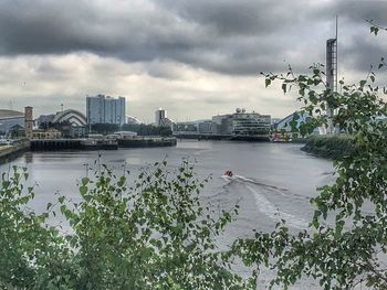 Scenic view of river by buildings against sky