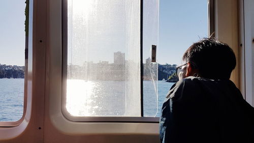 Rear view of man looking through window