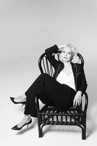 Portrait of young woman sitting on chair against white background