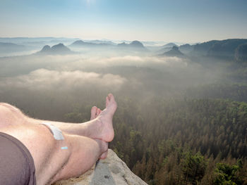 Hiker lie on edge of rock massif and relax. view over crossed legs of resting body into landscape