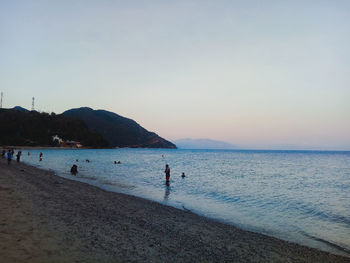 People on beach against clear sky