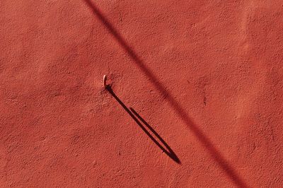 Shadow of iron hook on red wall