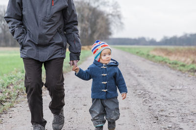 Low section of father with daughter walking on road