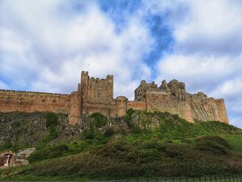 Low angle view of historic building against sky. bamburgh castle. northumbria. uk