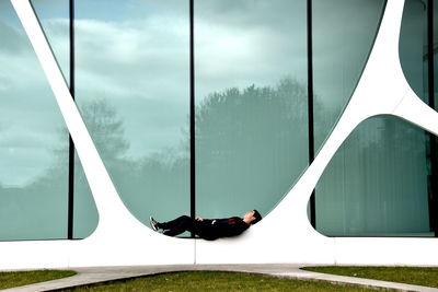 Young man lying against building