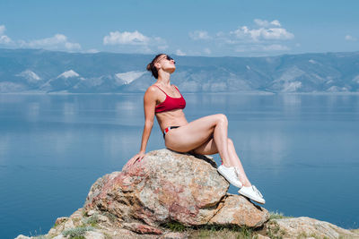 Young woman standing on rock against mountains