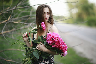 Woman standing by pink flowering plant