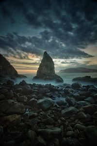 Rocks on beach against sky during sunset