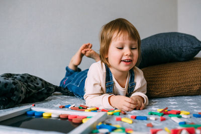 Child plays at home an educational game with a multi-colored magnetic puzzle