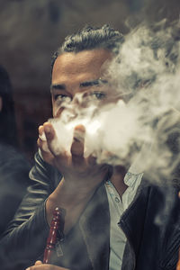 Portrait of young man playing with smoke