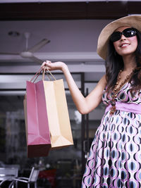 Woman wearing sunglasses and hat while holding shopping bags