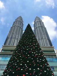 Low angle view of petronas towers and christmas tree against sky