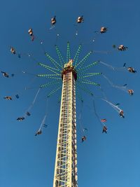 Low angle view of chain swing ride against clear blue sky