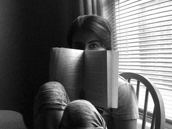 Portrait of young woman sitting with a book at home