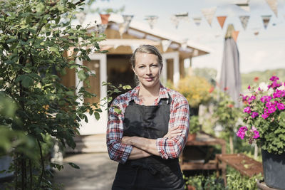 Portrait of confident woman with arms crossed against food store