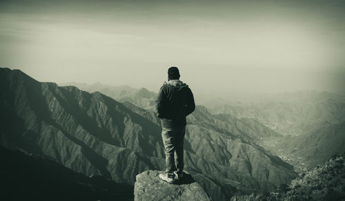 Rear view of man standing on mountain against sky