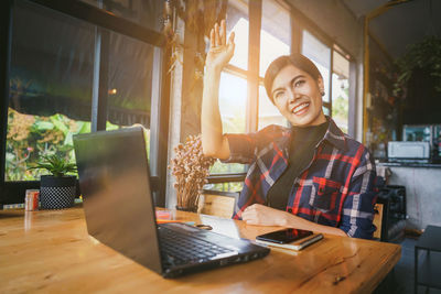 Young woman using mobile phone while sitting on table