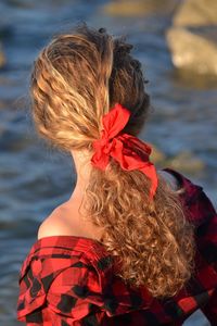 Woman hair tied with red ribbon against lake