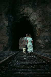 Rear view of people walking on railroad track