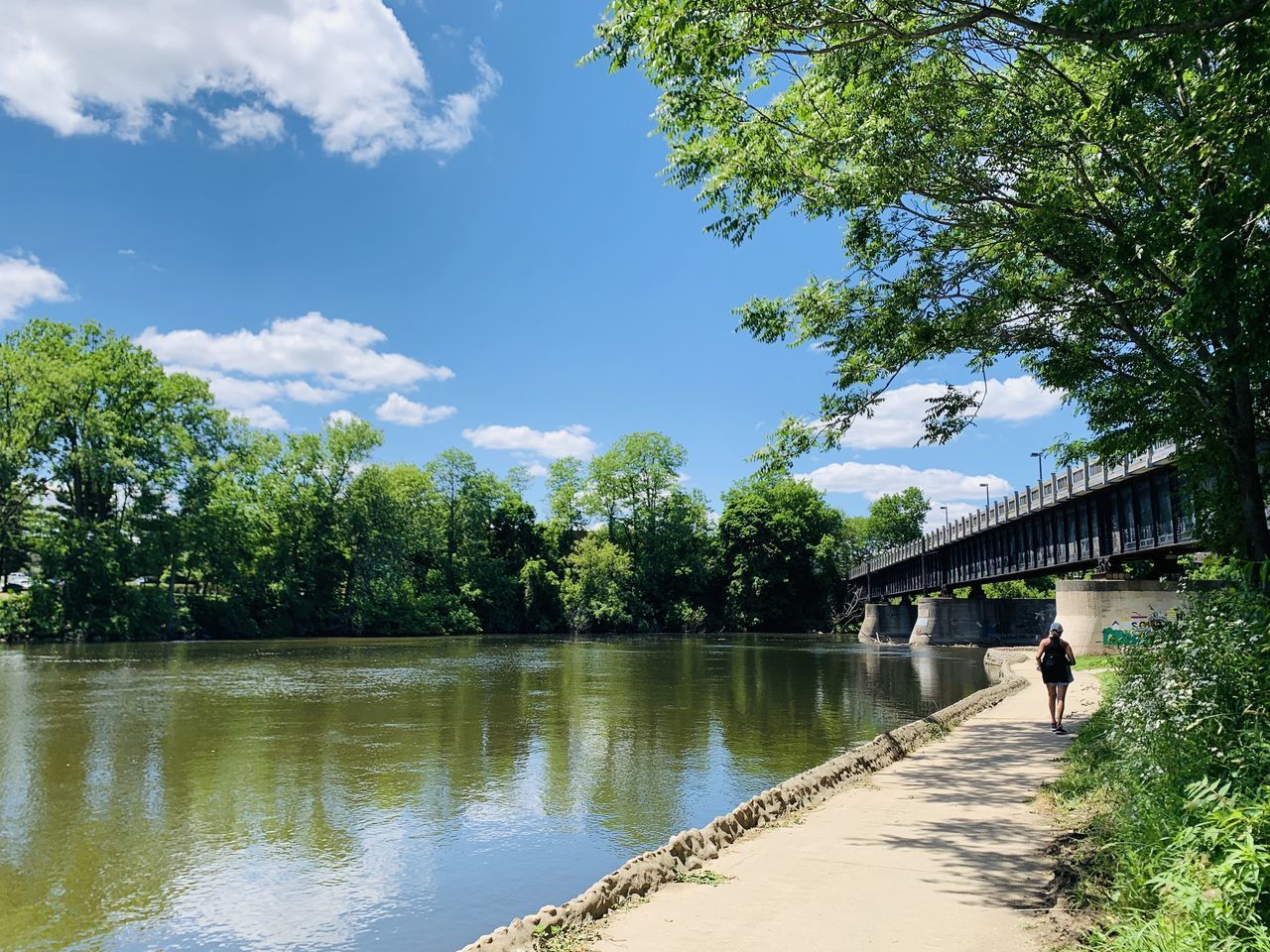 MAN WALKING BY CANAL AGAINST SKY