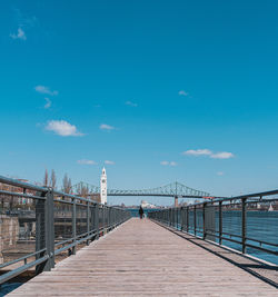 Footbridge over pier against blue sky