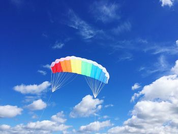 Low angle view of parachute flying against blue sky