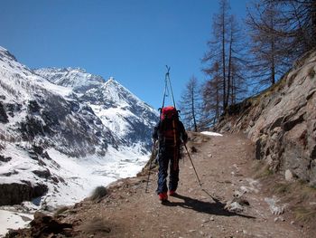 Rear view of man standing on snowcapped mountain